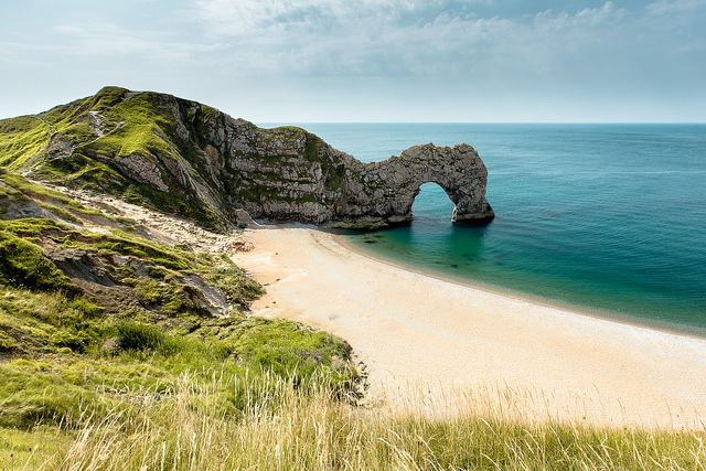 Golden sandy beach with unique rock formation, blue sky and turquoise sea.