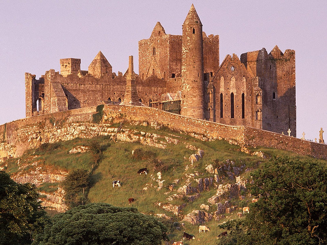 Historic castle set on a hill side with steep cliffs covered in grass under