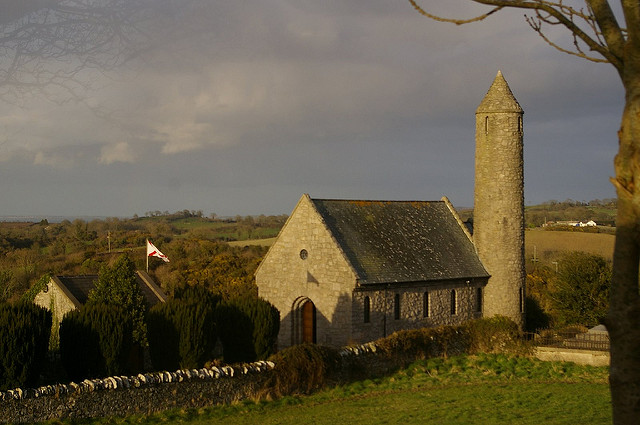 Historic church set in a green field with cloudy blue sky.