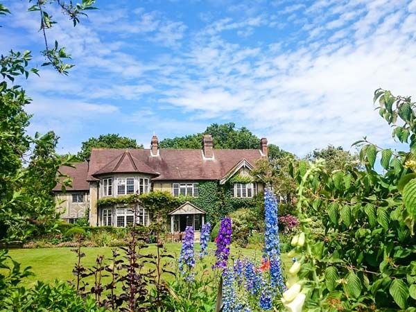 Mannor house surrounded by greenery and flowers. 