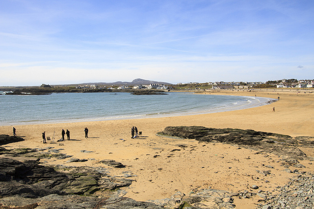 Golden sandy beach with a blue sky and fisherman near the sea