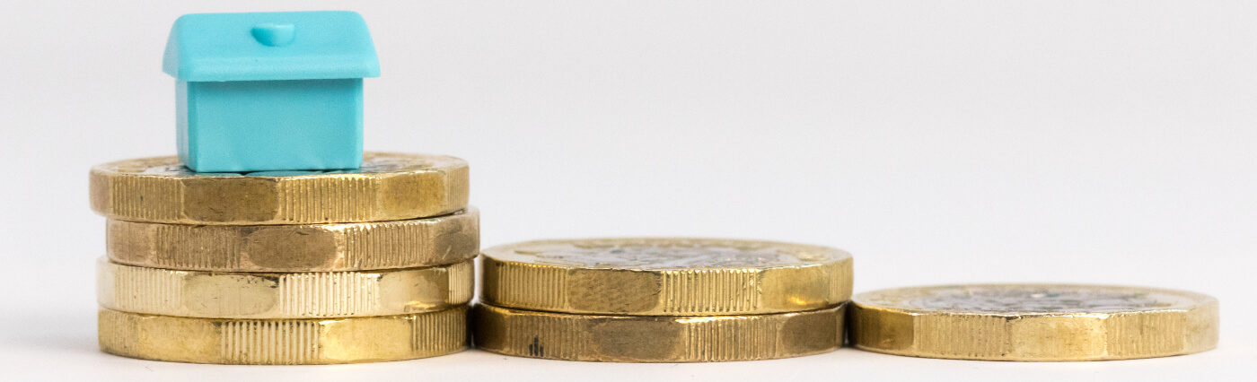 Pile of pound coins with monopoly house on top