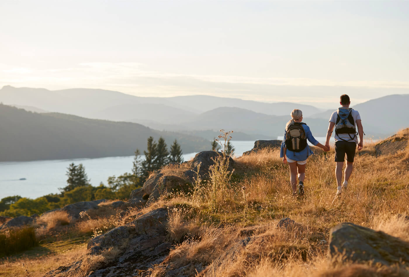 Couple walking through the fells overlooking a lake in Windermere