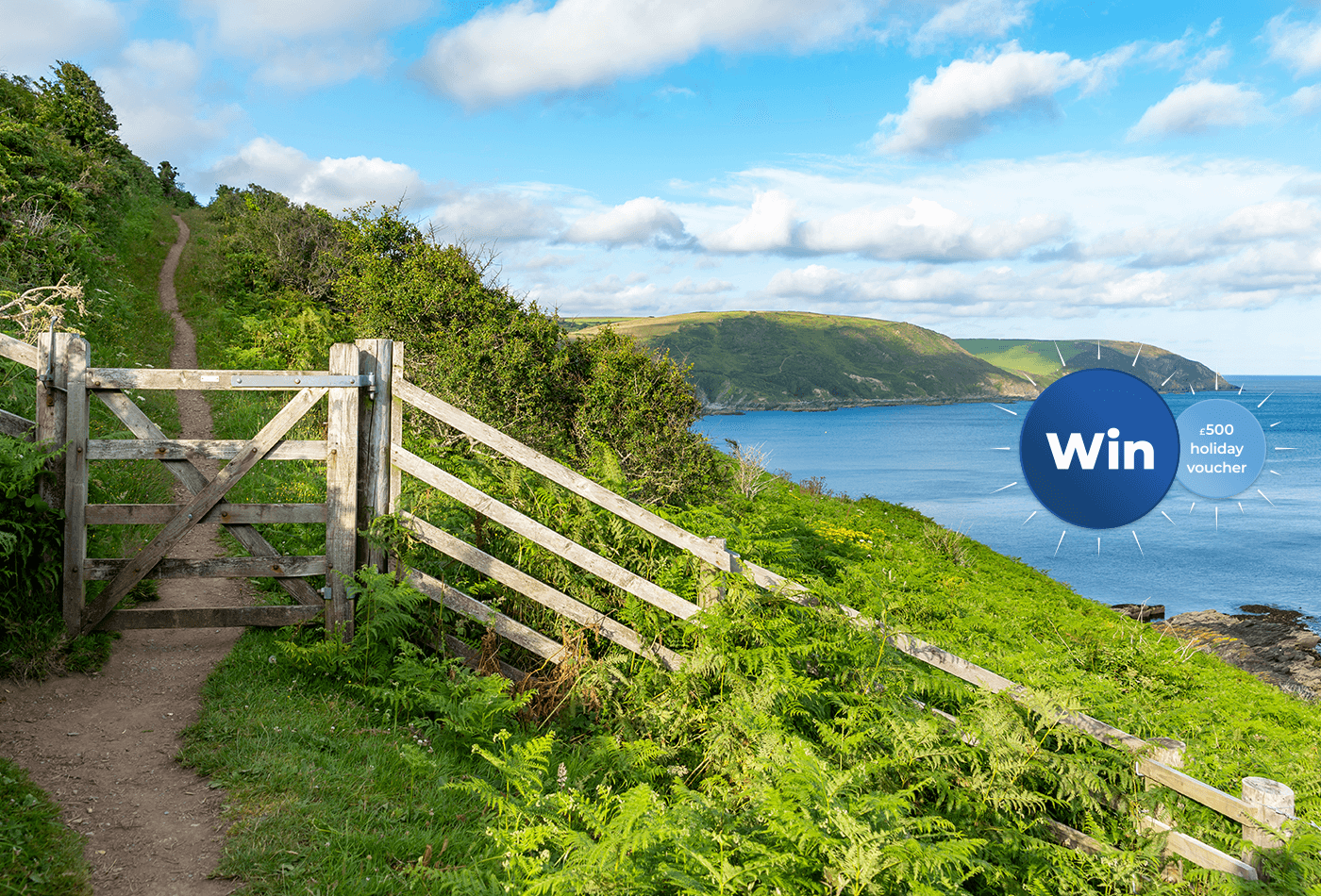 Wooden gate on a coastal path with sea and hills in the background