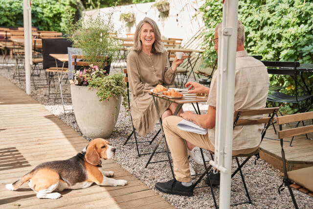 senior couple sitting outside restaurant with dog
