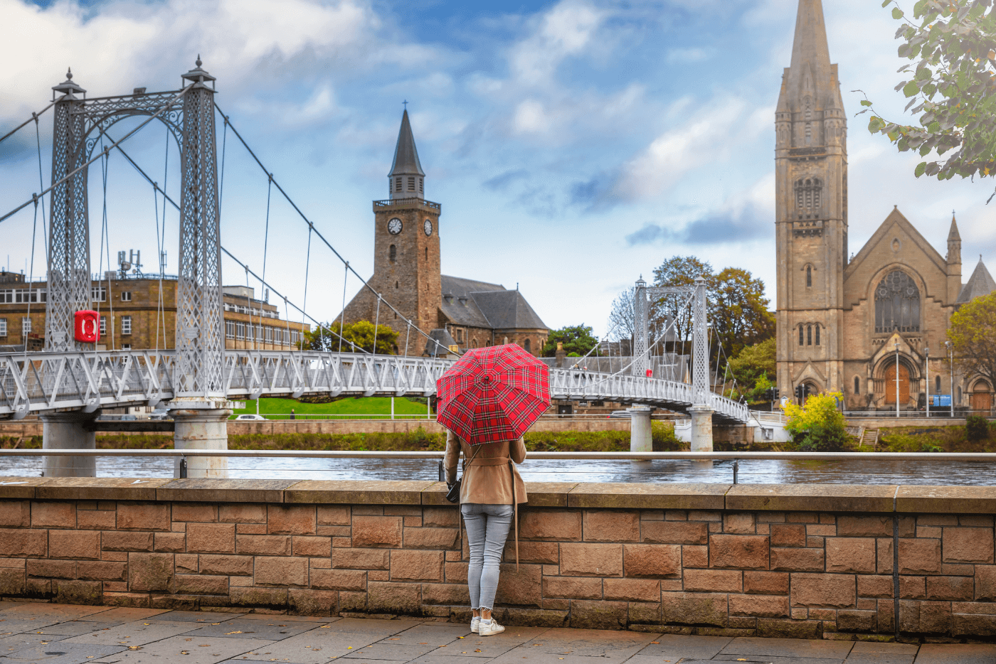 Woman with umbrella looking over cityscape of Inverness