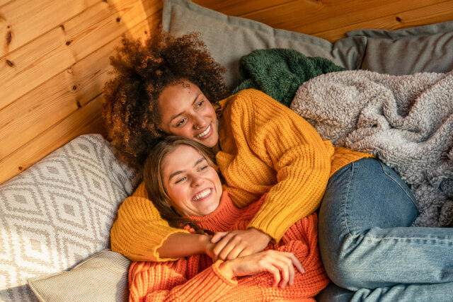 Female couple enjoy afternoon relaxation on the bed in log cabin