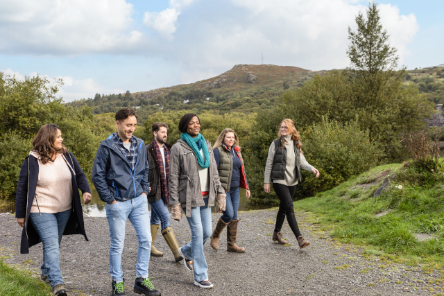Group of friends walking in the countryside with hill in background