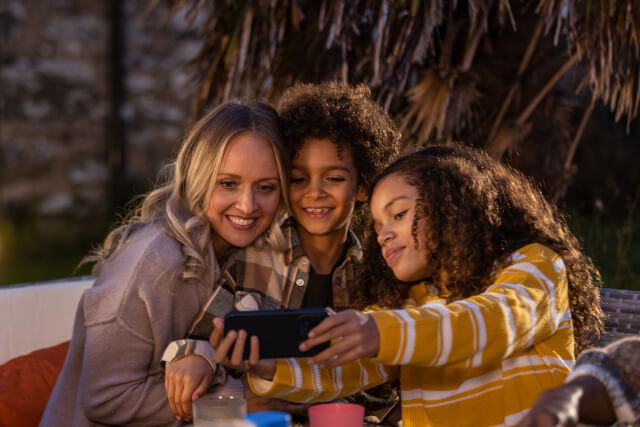 Mum with two children taking a selfie in the garden, in the evening time.