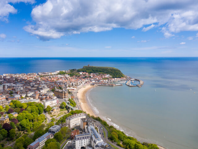 Aerial view of Scarborough harbour town, with blue skies and blue shores