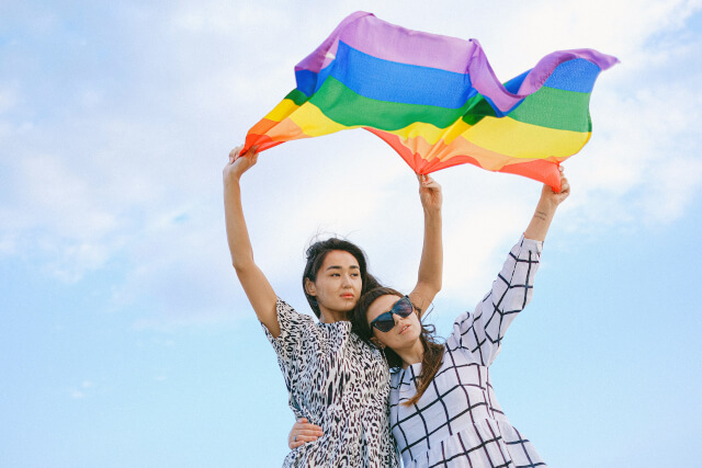 a couple holding up a pride flag in the wind