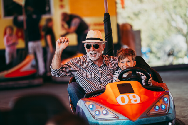 grandfather and grandson enjoying bumper cars at an amusement park