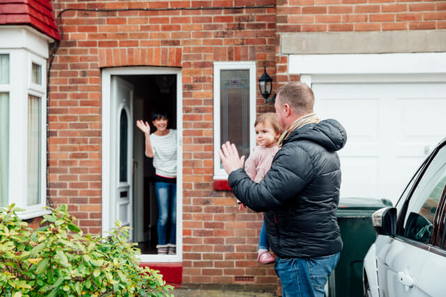 woman saying goodbye to man with child