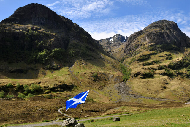 A Scottish flag with three mountains in the background
