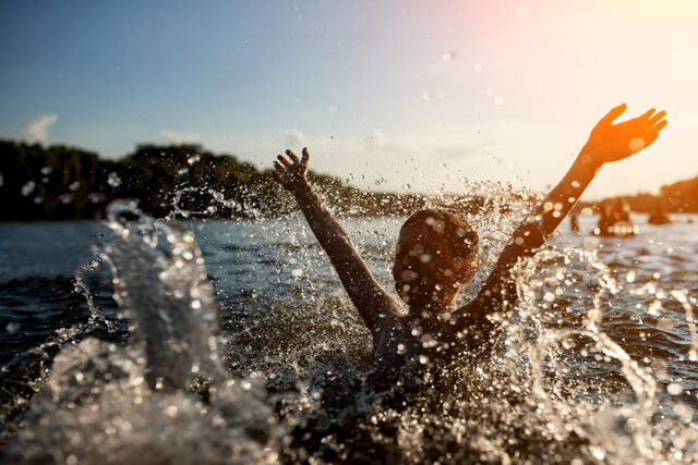 A young child making a splash in an open body of water