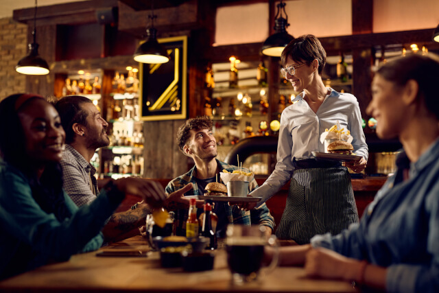 Waitress serving a table, handing a man food at a pub