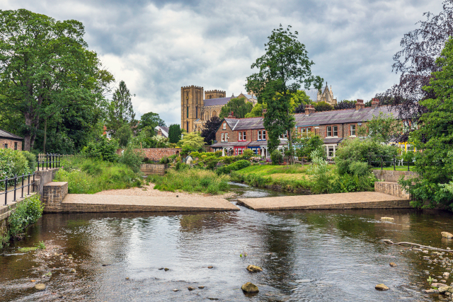 A view of the ford that crosses over the River Skell in Ripon, North Yorkshire, with the towers of Ripon Cathedral visible in the background