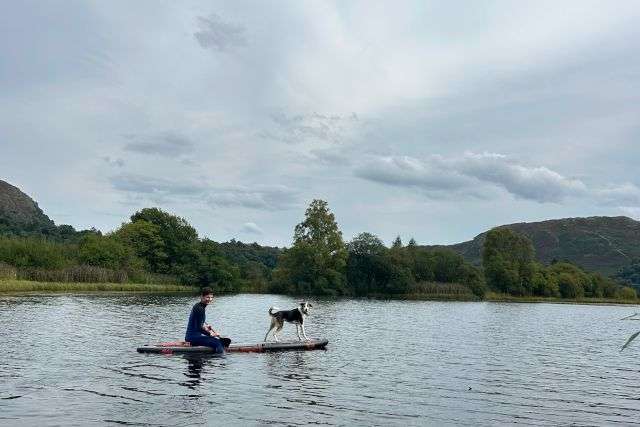 A photo of a man and his dog paddleboarding on Grasmere