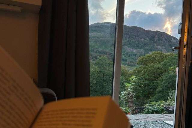 photo of a lady reading a book in her cottage