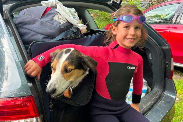 A photo of a young girl and her dog ready to go paddle boarding