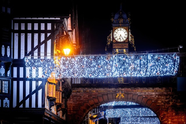 Chester Eastgate clock and bridge decorated with Christmas lights at night time.