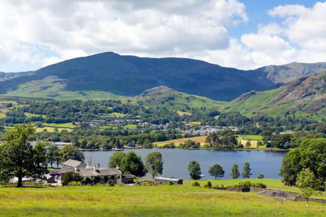 Coniston Water in the Lake District, with mountains and blue sky and white clouds on a beautiful summer day.
