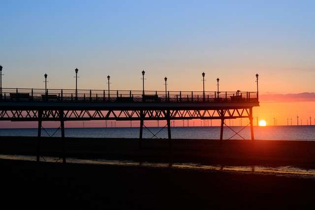 Skegness pier front with sun setting.