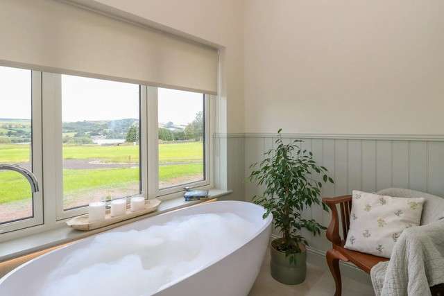 Freestanding bath with countryside views at Bramble Cottage.
