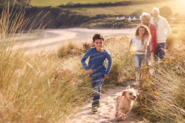 A family walking along a coastal path with their dog.