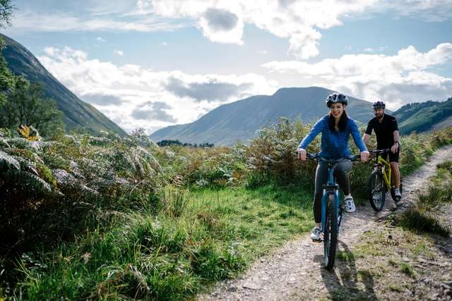 Two people are bikes through the countryside.