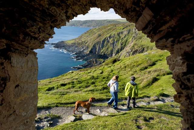 View of dog walkers from archway along Cornwall's coast.