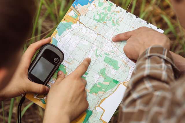 Two people pointing to a location on a map whilst geocaching