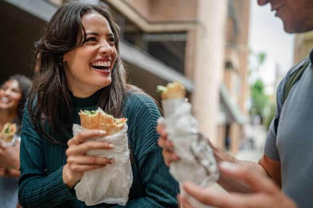 Two people conversing whilst eating street food