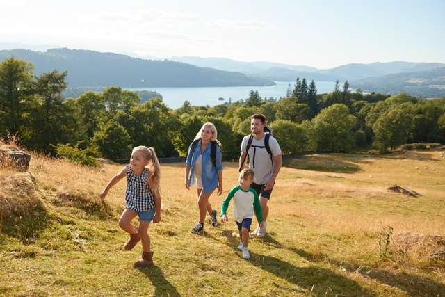 A family hiking in the UK countryside with a lake in the distance.