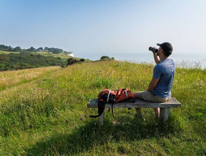 A man sat on bench overlooking White Cliffs of Dover