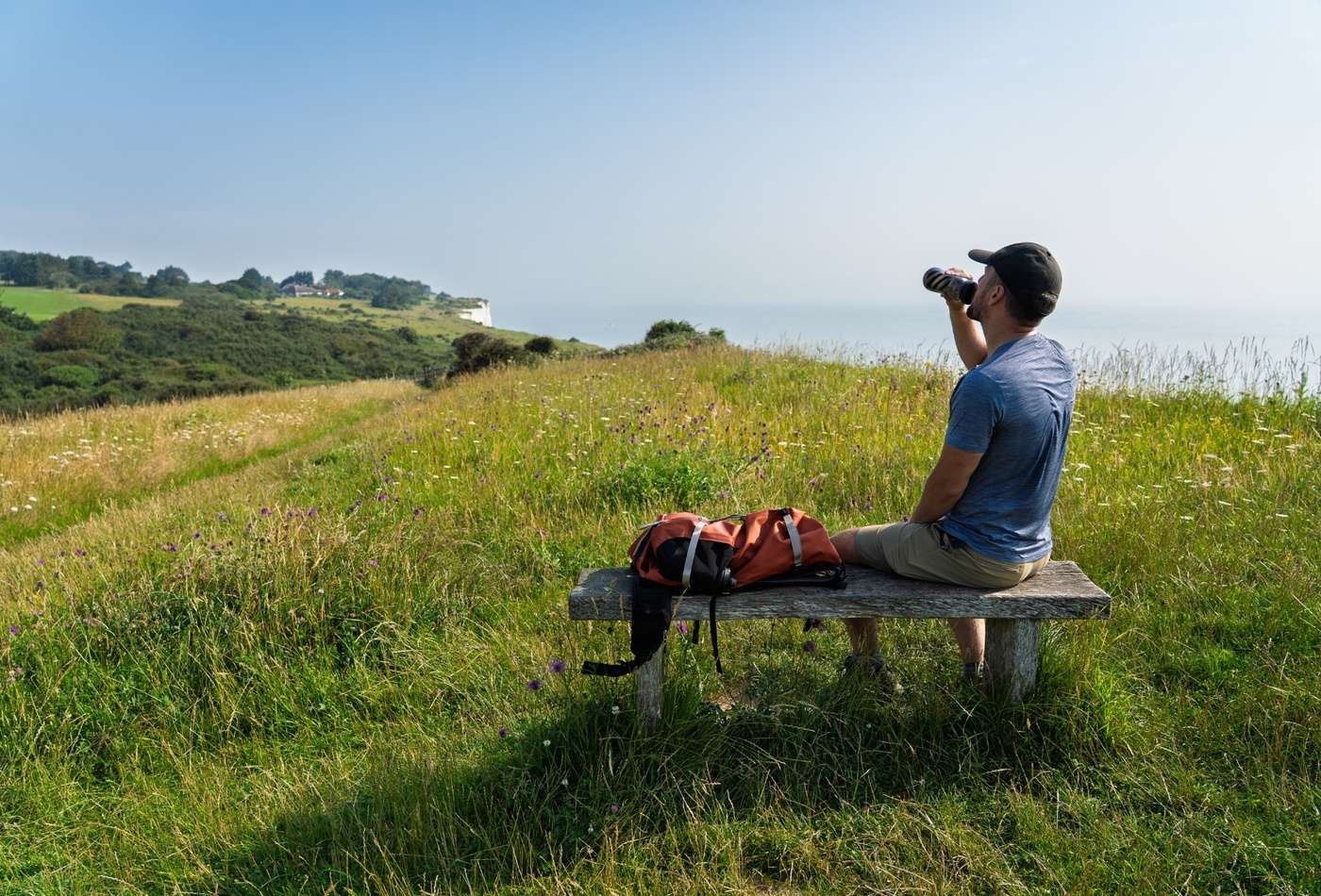 A man sat on bench overlooking White Cliffs of Dover