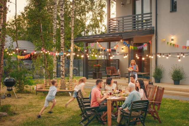 Family having a barbecue whilst staying at a holiday cottage next to a wooded area