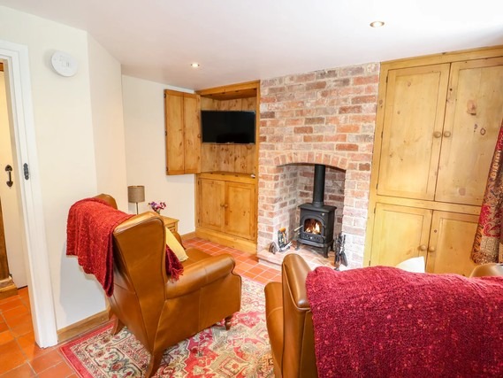 Characterful sitting room with armchairs and woodburning stove in Lizzies Cottage.