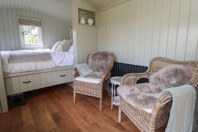 Studio-style living area with double bed and arm chairs in The Garden Hut.