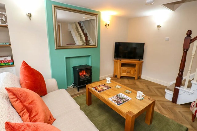 Living area with TV and woodburning stove at The Old Dairy.