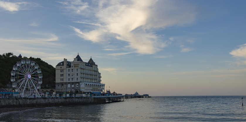 Llandudno north Wales united kingdom 02 June 2023 Grand Hotel and Ferris wheel on Llandudno Pier a Grade I listed pier in the seaside resort of Llandudno in north Wales during evening light