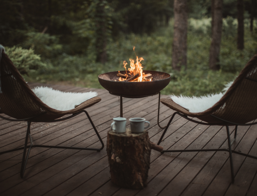 Outdoor setup with a fire pit and chairs on a wooden deck at a glamping site in the UK.