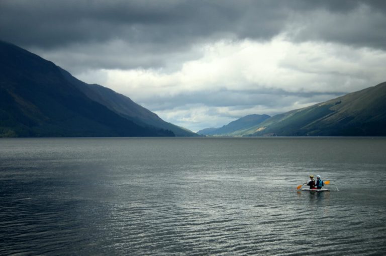 Two people kayaking in Loch Ness with grey clouds above