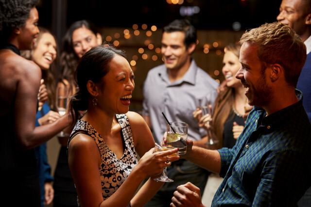 Adults dancing and drinking at a rooftop bar