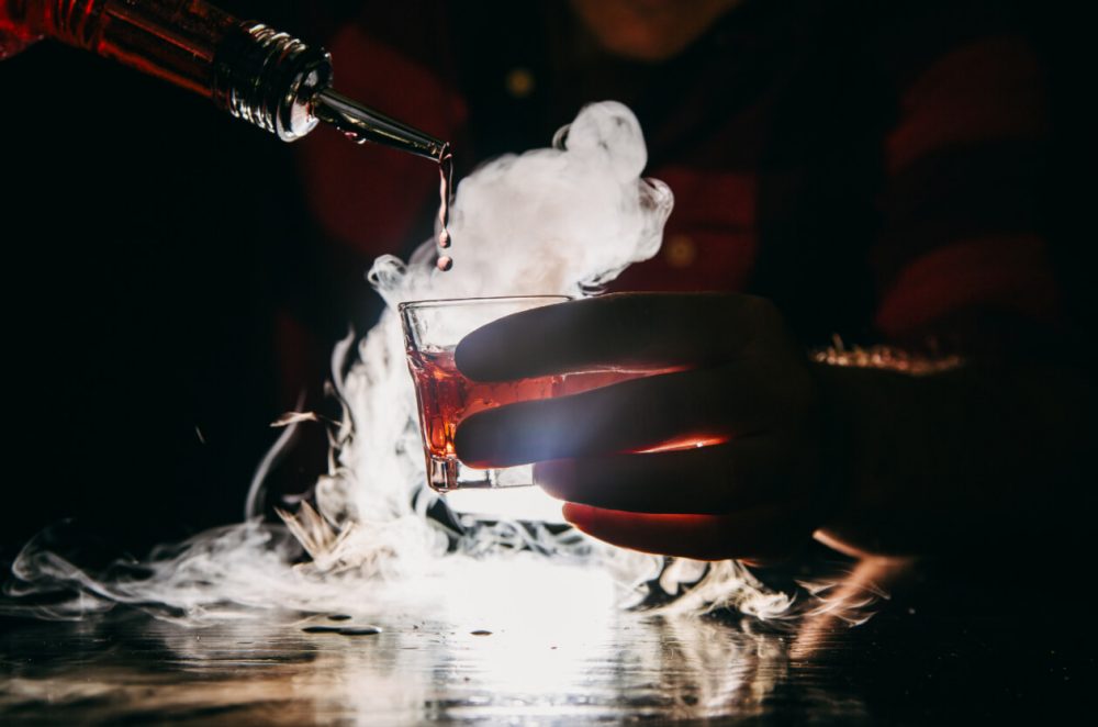 Bartender pouring whisky with dry ice