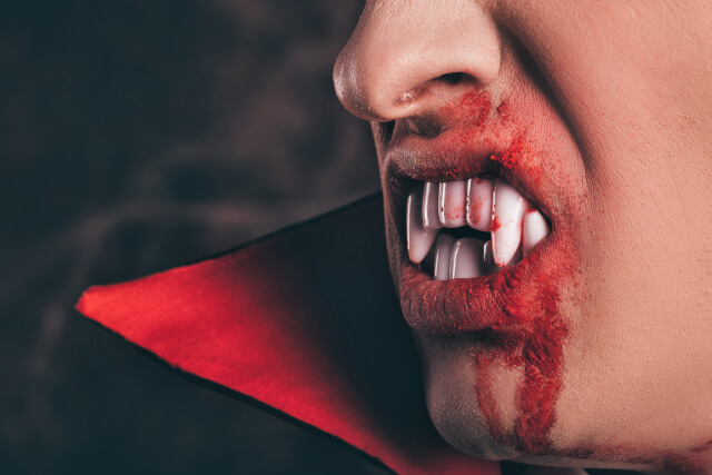 Close up of vampires fangs and cloak