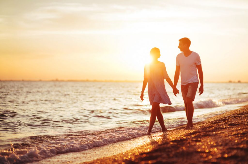 Couple walking on beach at sunset