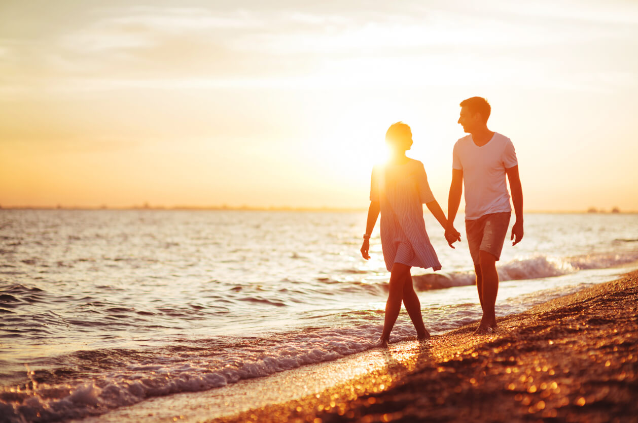 Couple walking on beach at sunset