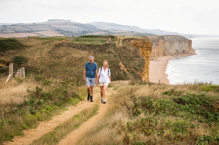 A couple walking along West Bay, Jurassic Coast, cliffs in background