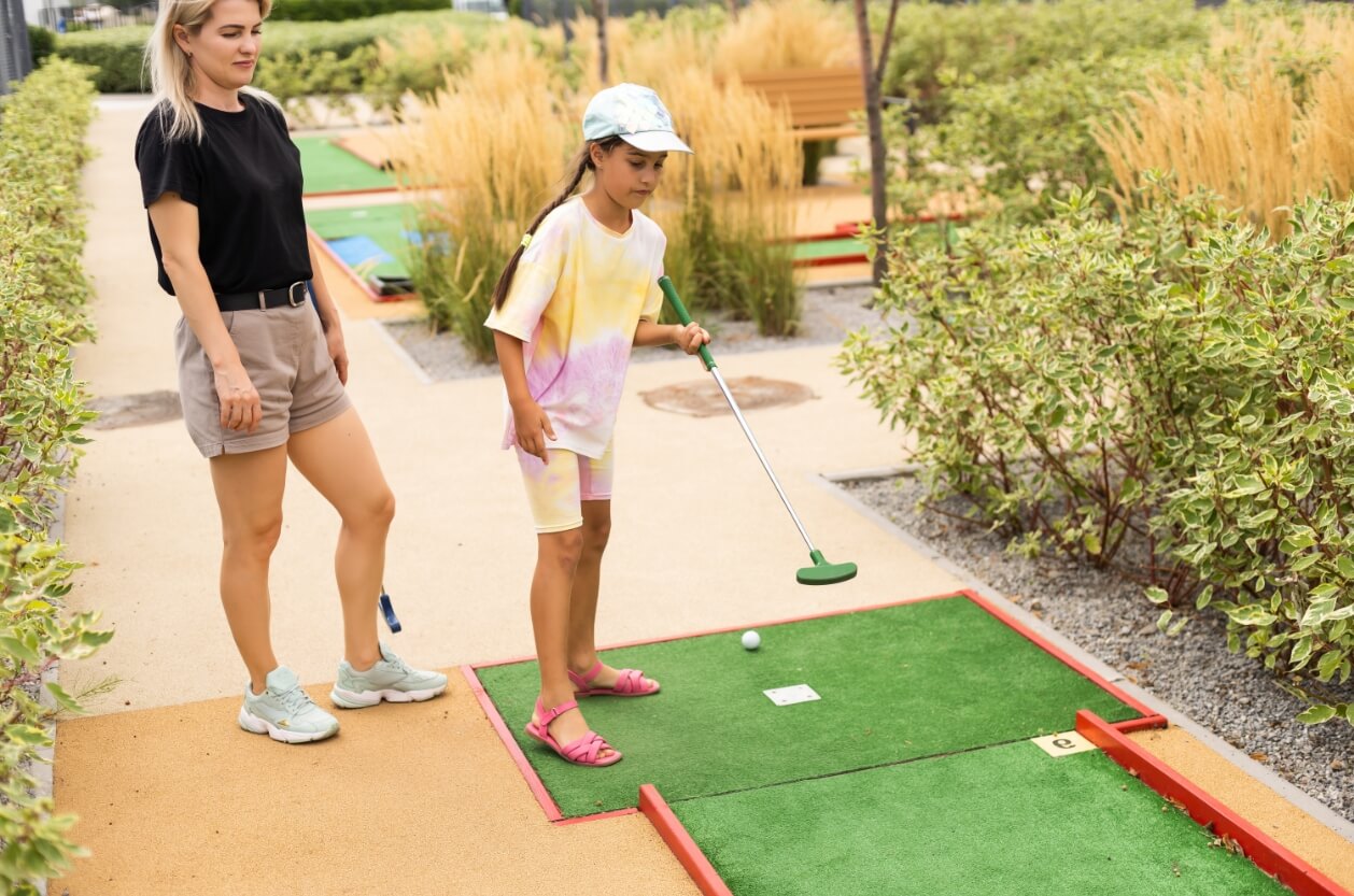Mother and daughter playing a game of outdoor mini golf